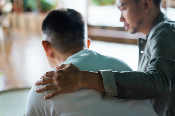 2 mannen zitten naast elkaar waarbij 1 man een hand op de schouder van de andere man legt