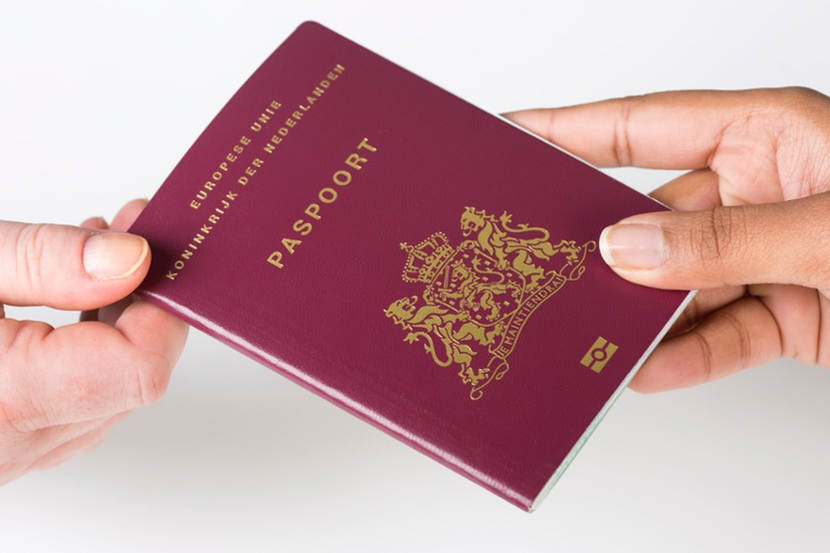 2 handen met een Nederlands paspoort. 